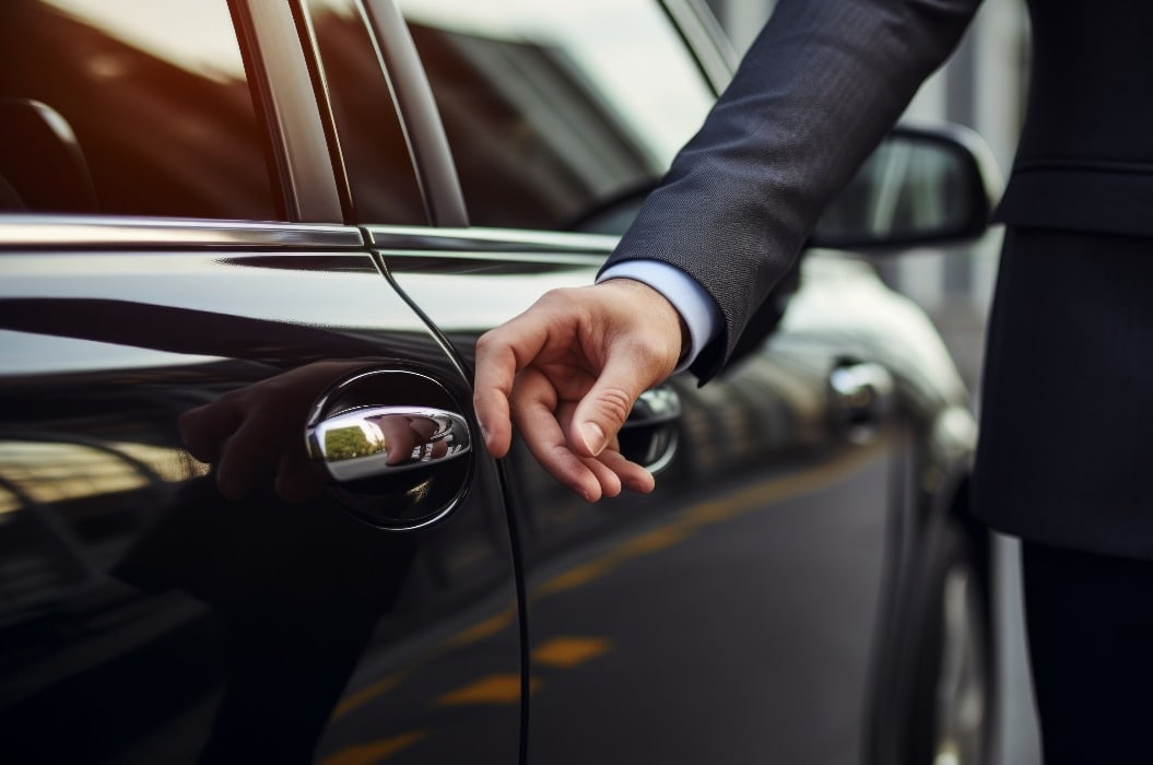 A businessman's hand reaches for the door of a luxury car. Background with selective focus