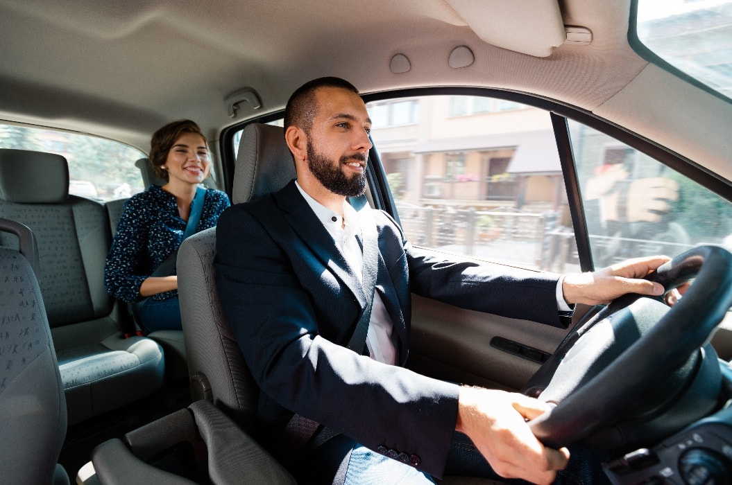 Taxi driver sitting in a car with businesswoman